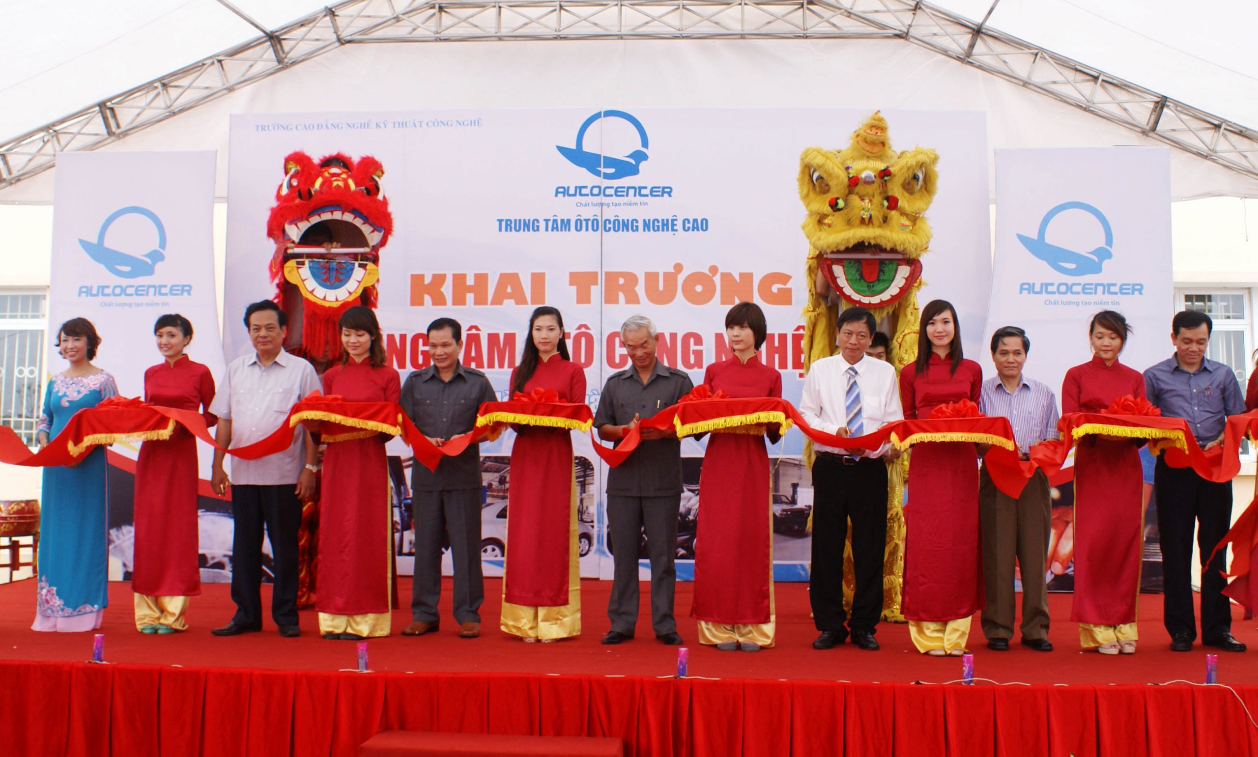 Sân khấu lễ khánh thành với backdrop khai trương và hàng khách cắt băng