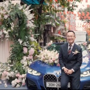 Chú rể bên xe hoa BMW trước cổng hoa monogram QK