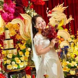 Cô dâu váy trắng cầm hoa đỏ trước tráp rồng phượng