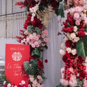 Cổng hoa lễ ăn hỏi tại nhà màu đỏ hồng phấn và bảng Nhà có hỷ
