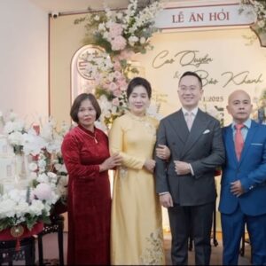 Hai gia đình chụp ảnh trước backdrop lễ ăn hỏi hồng pastel