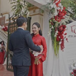 Cô dâu áo dài đỏ chú rể trước cổng cưới hoa hồng đỏ