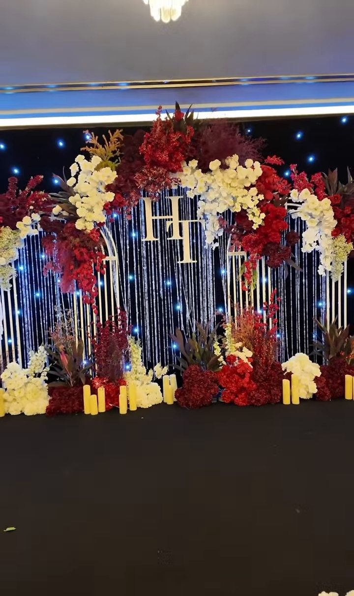 Backdrop hoa tươi đỏ vàng trắng kết vòm monogram tên cô dâu chú rể