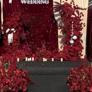 Backdrop hoa lá tươi tông đỏ rượu vang và rèm nhung sân khấu tiệc cưới