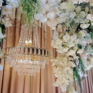 Cận cụm lan hồ điệp trắng hoa baby và đèn chùm pha lê trên rèm nhung champagne