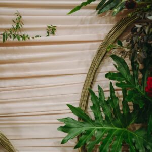 Chi tiết vải satin kem xếp nếp ngang và vòng tre vàng lá xanh backdrop ăn hỏi