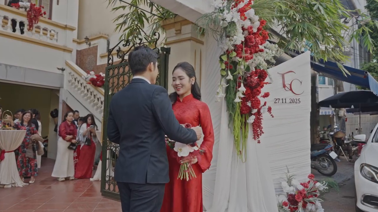 Chụp ảnh cô dâu áo dài ngày cưới áo dài đỏ chú rể trao hoa trước cổng voan monogram T&C