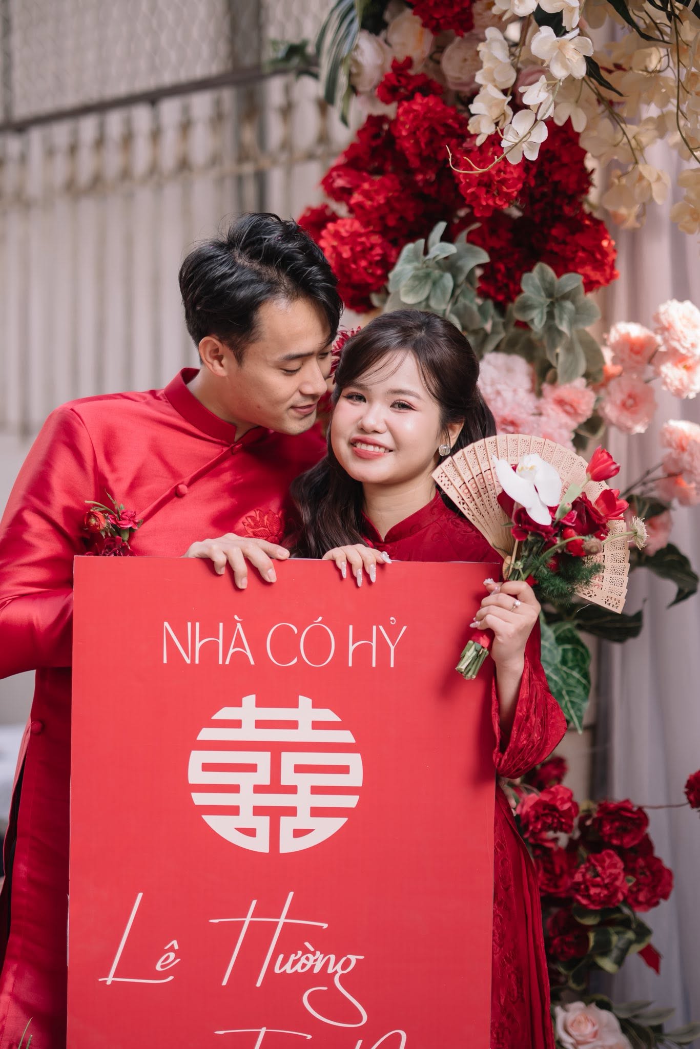 Chụp ảnh cô dâu áo dài ngày cưới cùng chú rể cầm bảng Nhà có hỷ Lê Hương Tiến Nam