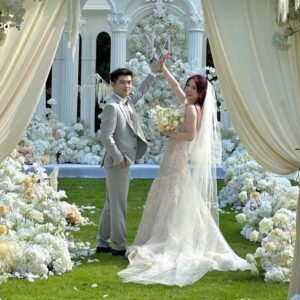 Chụp ảnh cưới ngoài trời cặp đôi giơ tay vui mừng dưới vòm hoa trắng voan kem
