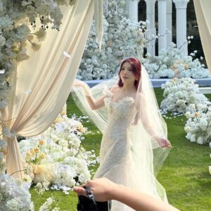 Chụp ảnh cưới ngoài trời cô dâu xoay váy trong vườn hoa trắng vòm voan kem cột La Mã