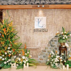 Cổng hoa cưới nhà hàng tường đá hoa thiên điểu lá chuối hoa trắng nến monogram