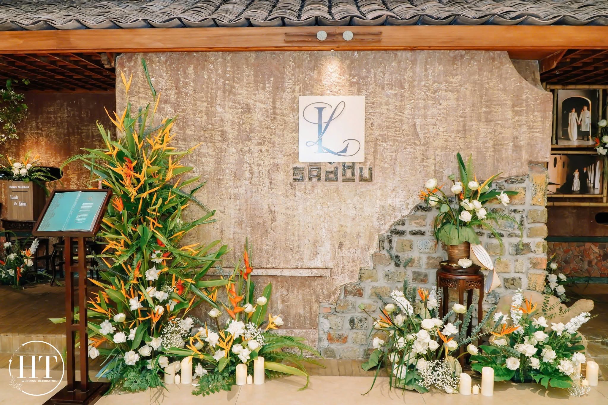Cổng hoa cưới nhà hàng tường đá hoa thiên điểu lá chuối hoa trắng nến monogram