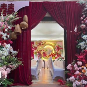 Cổng rèm nhung đỏ vén đèn mây chữ hỷ hoa hồng trắng đỏ cam nhìn vào sảnh tiệc
