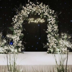 Cổng tròn hoa trắng baby neon tên Tín Nhi phông sao đen sân khấu trắng