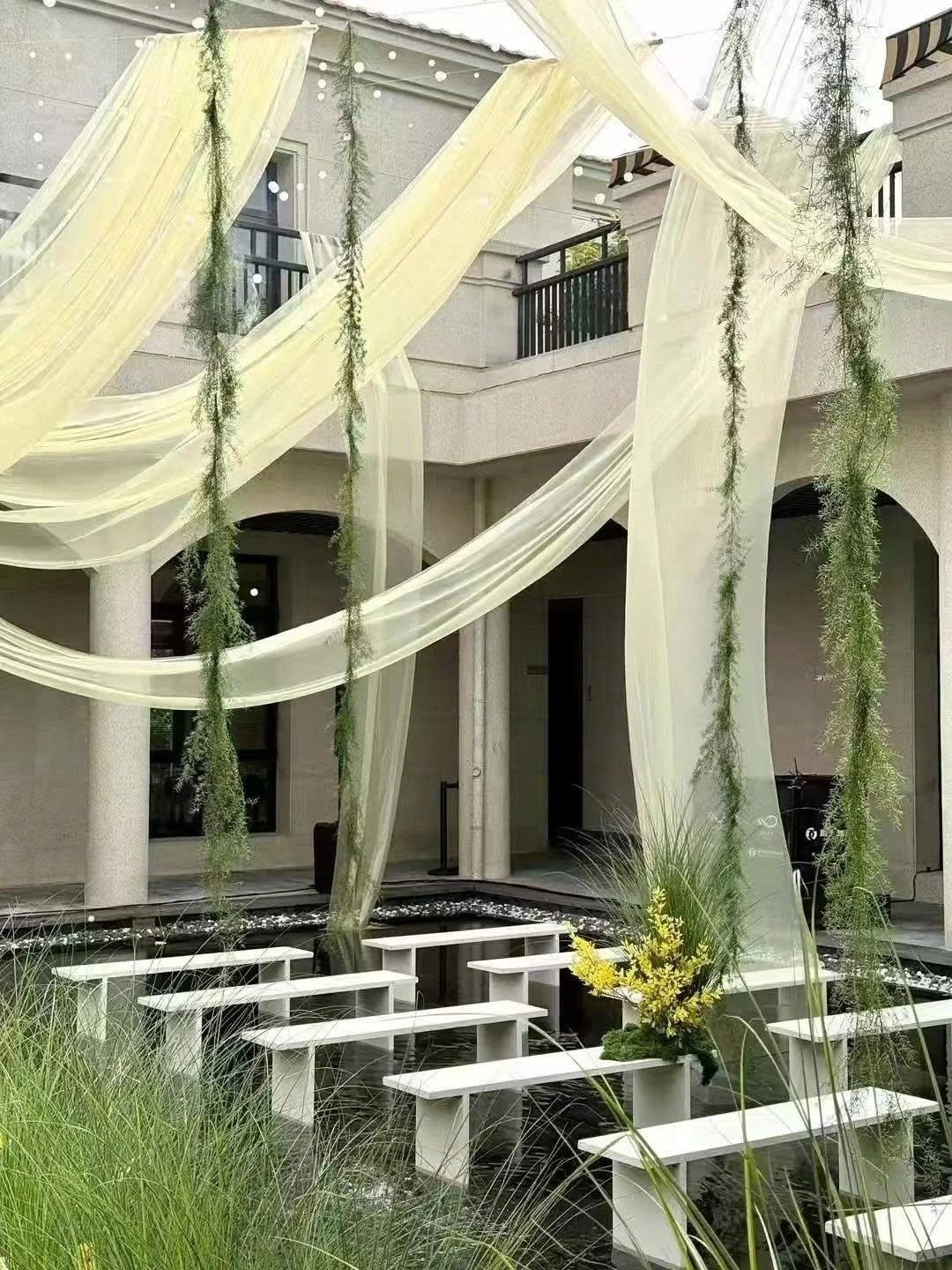 Ghế băng trắng đặt trên mặt nước sân biệt thự voan vàng dây lá xanh rủ trang trí tiệc cưới biệt thự