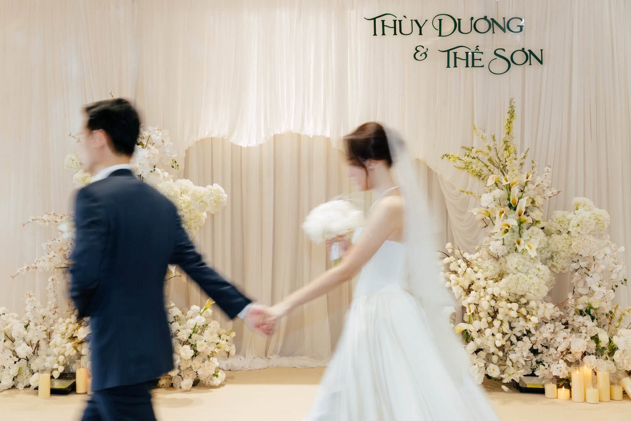 Khoảnh khắc đẹp ngày cưới chú rể dắt cô dâu đi trước backdrop rèm kem Thùy Dương Thế Sơn