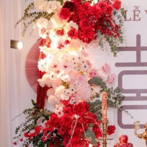 Khối hoa hồng đỏ cẩm chướng đồng tiền hồng phấn lá bạch đàn quạt giấy đỏ backdrop chữ hỷ lễ vu quy