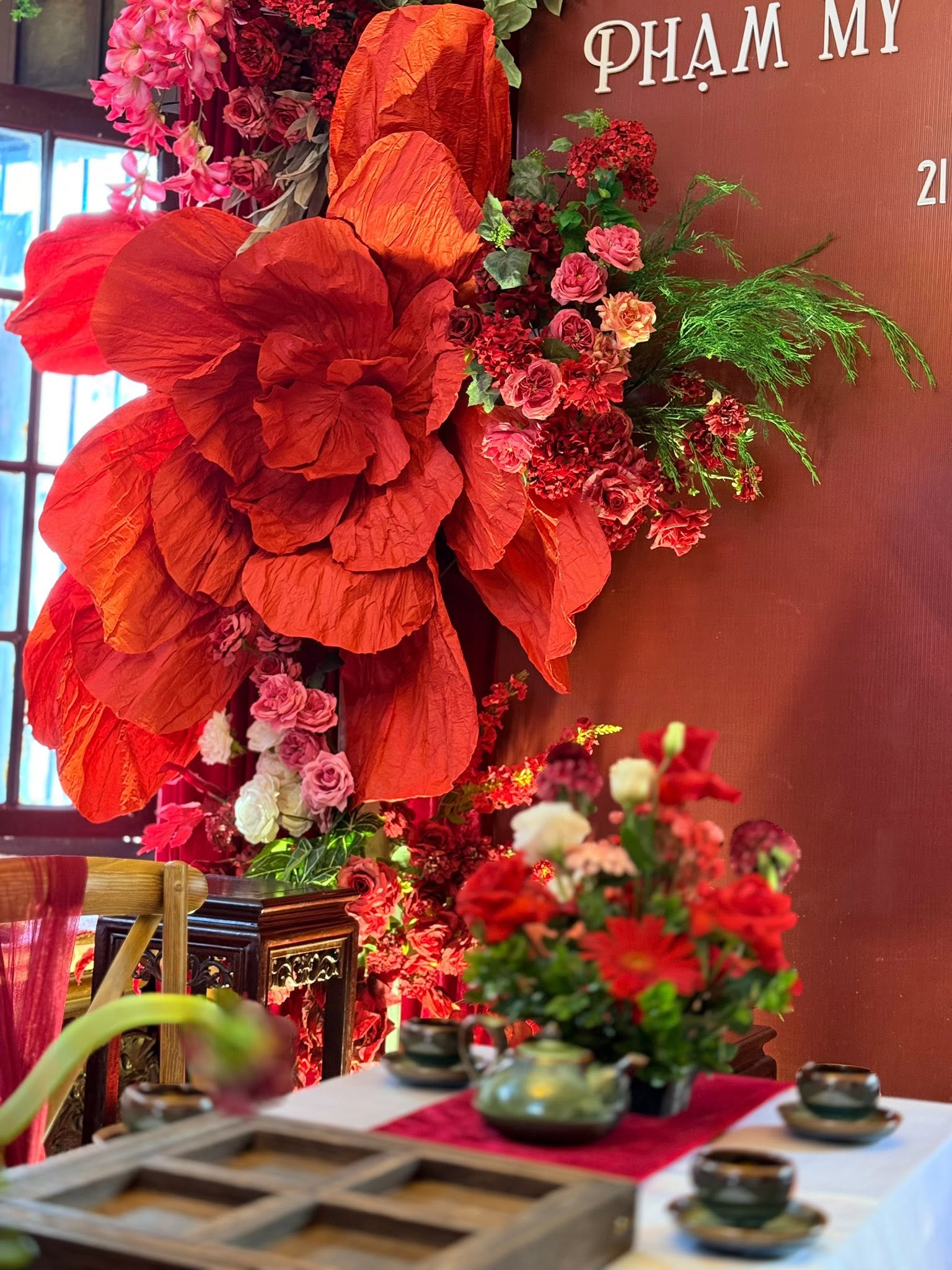 Lễ ăn hỏi Phạm My backdrop đỏ trầm chữ tên trắng hoa giấy khổng lồ cam đỏ bàn trà ấm chén men xanh