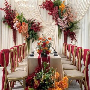 Lễ thành hôn Bùi Hân Ngọc Anh backdrop vải kem rủ hoa đỏ cam bàn trà dài ghế gỗ voan đỏ