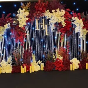 Sảnh cưới tone đỏ sân khấu vòm trắng rèm pha lê monogram HH hoa đỏ trắng phông sao đen