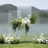 Tấm acrylic mờ xếp chồng so le cụm hoa trắng treo ngang cỏ đuôi chồn rủ đám cưới bên hồ