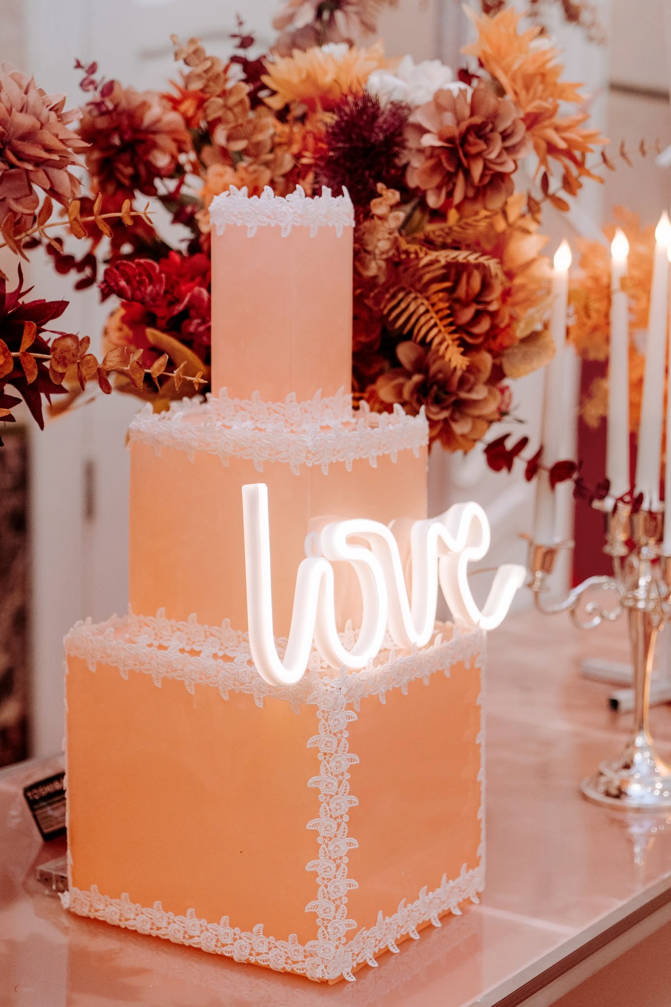 Bánh cưới 3 tầng màu cam đào Bánh cưới 3 tầng màu cam đào viền ren trắng với đèn neon love