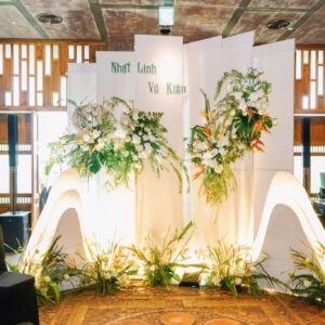 Tiệc cưới Nhật Linh Vũ Kiên backdrop trắng chữ xanh hoa thiên điểu