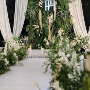 Tiệc cưới tone xanh lá trắng tường lá greenery monogram PH rèm trắng lối đi hoa trắng