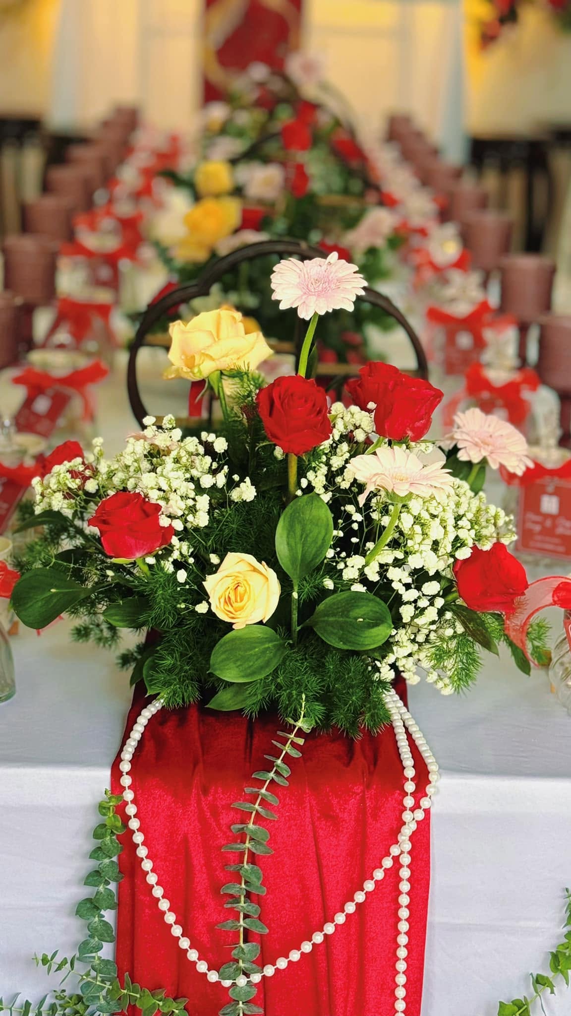 Bình hoa hồng vàng đỏ đặt trên bàn dài của lễ tân hôn