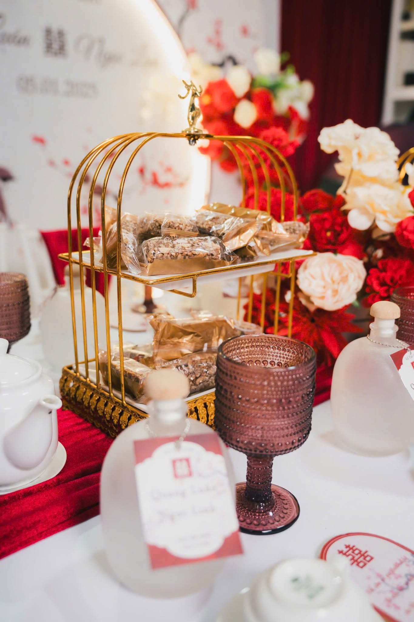 Lồng chim bánh, chai tag, ly tím trên bàn dài lễ vu quy